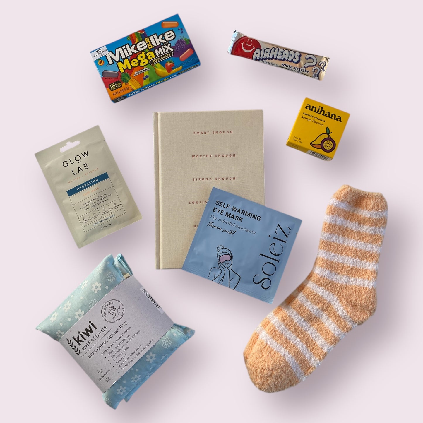 Contents of our self care gift box including, Kiwi wheat bag, glow lab face mask, wrm fluffy socks, anihana shower steamer, american candy, soleiz eye warming mask and awesome inc gratitude jornal.