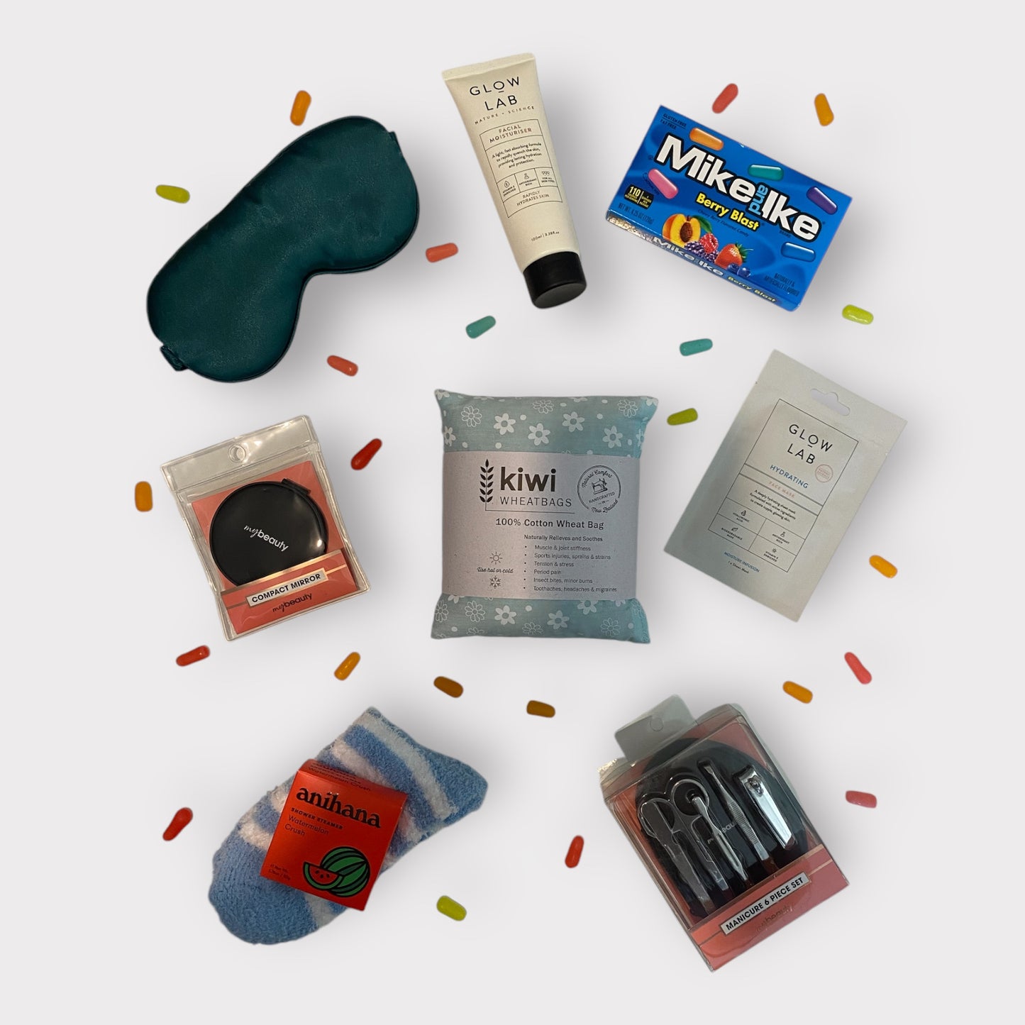 Contents of self care gift box including, silk eye mask, glow lab face wash, american candy, little mirror, kiwi wheatbag, glow lab face mask, fluffy socks, anihana shower steamer and nail care kit.