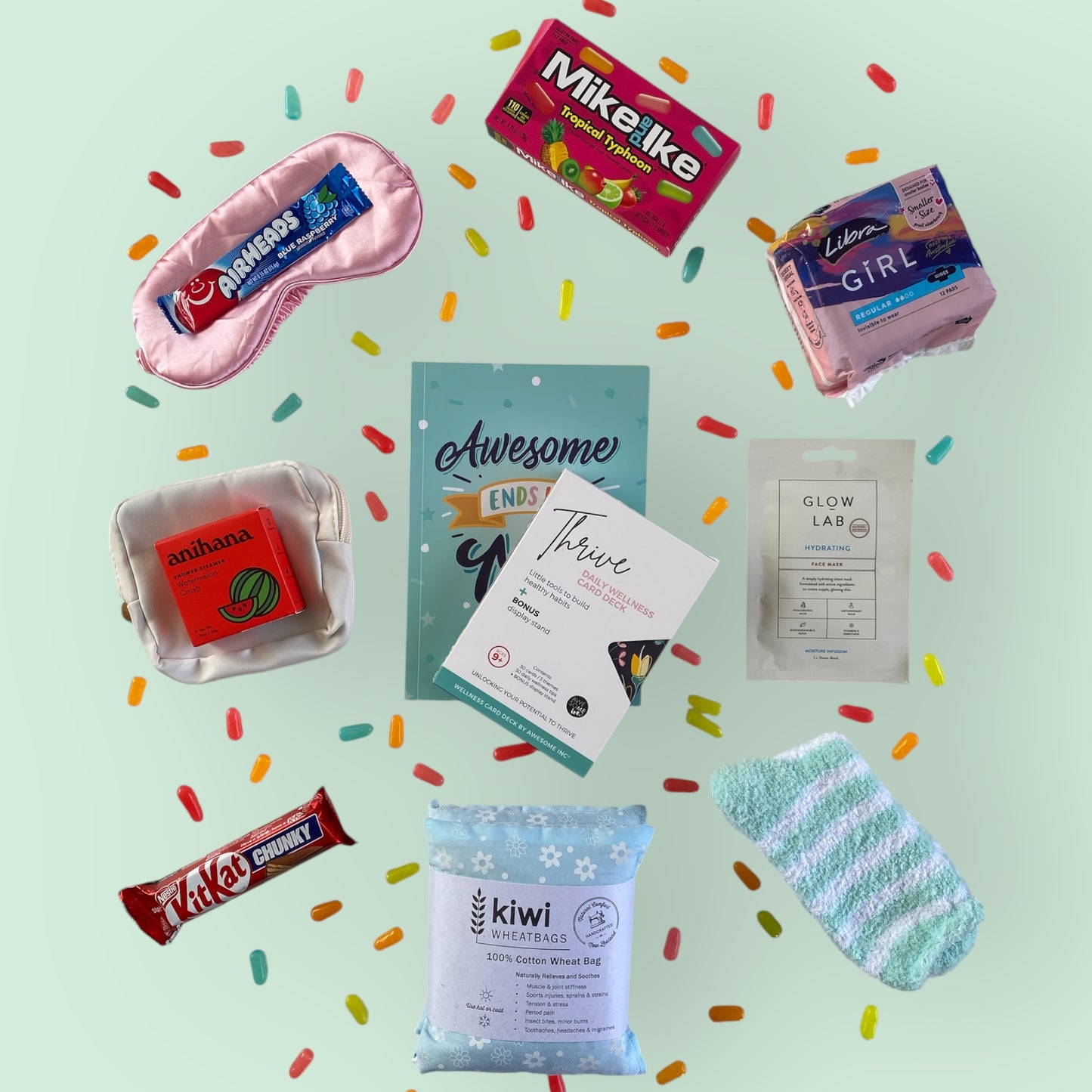 Contents of tween gift box on display. Eye mask, airheads candy, Mike and Ike candy, libra teen pads, anihana shower steamer, little purse, awesome ends in me journal, thrive wellness cards, glow lab face mask, kit kat, kiwi wheatbag and fluffy socks.