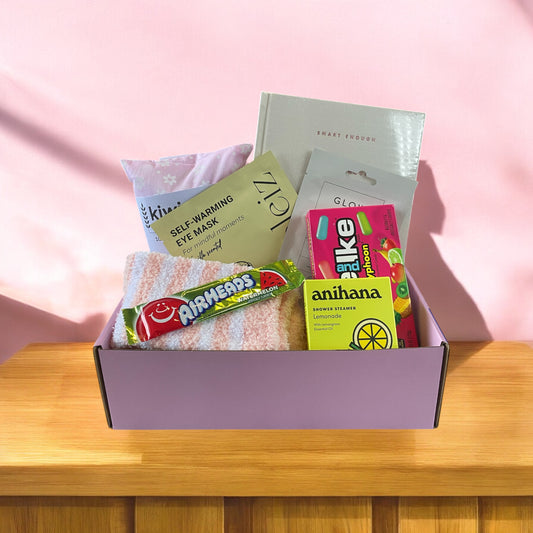 Gift box full of pamper treats. Fluffy socks, shower steamer, wheat bag, gratitude journal, American treat. 