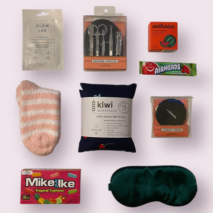 Close up of items in the gift box. Face mask, nail kit, shower steamer, fluffy socks, wheat bag, little mirror, American candy and eye mask 