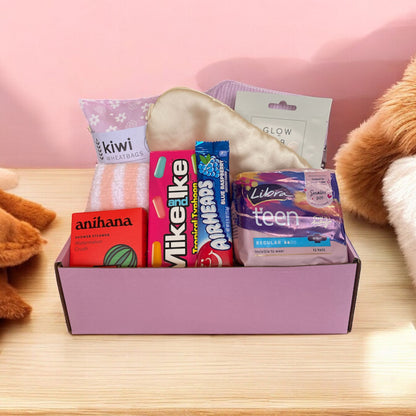 Gift box with pampering self care items in in. Wheat bag, fluffy socks, face mask, shower steamer and pads 