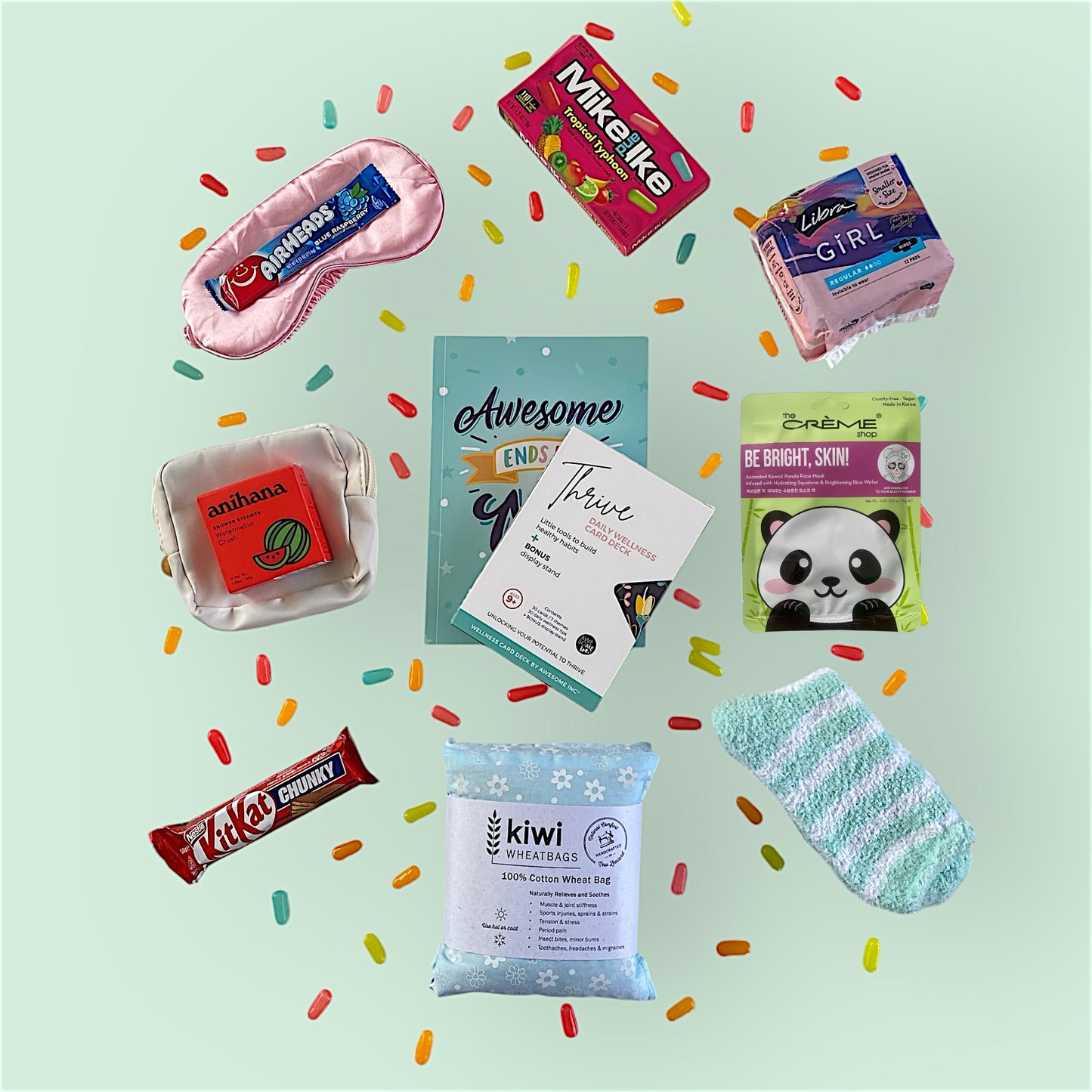 Contents of tween gift box on display. Eye mask, airheads candy, Mike and Ike candy, libra teen pads, anihana shower steamer, little purse, awesome ends in me journal, thrive wellness cards, glow lab face mask, kit kat, kiwi wheatbag and fluffy socks.