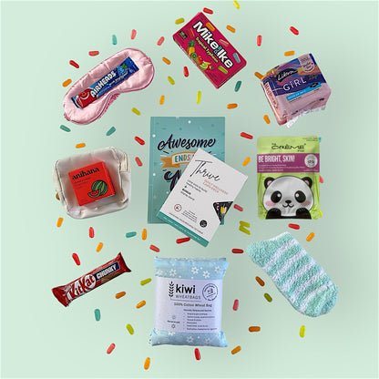 Contents of tween gift box on display. Eye mask, airheads candy, Mike and Ike candy, libra teen pads, anihana shower steamer, little purse, awesome ends in me journal, thrive wellness cards, glow lab face mask, kit kat, kiwi wheatbag and fluffy socks.