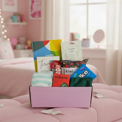 Beautiful gift box displaying tems. Create your own sunshine gratitude journal, American candy, Thrive wellness cards, kiw wheat bag, glow lab face mask, kit kat chocolate bar, airhead candy, eye mask, fluffy socks and shower steamer.